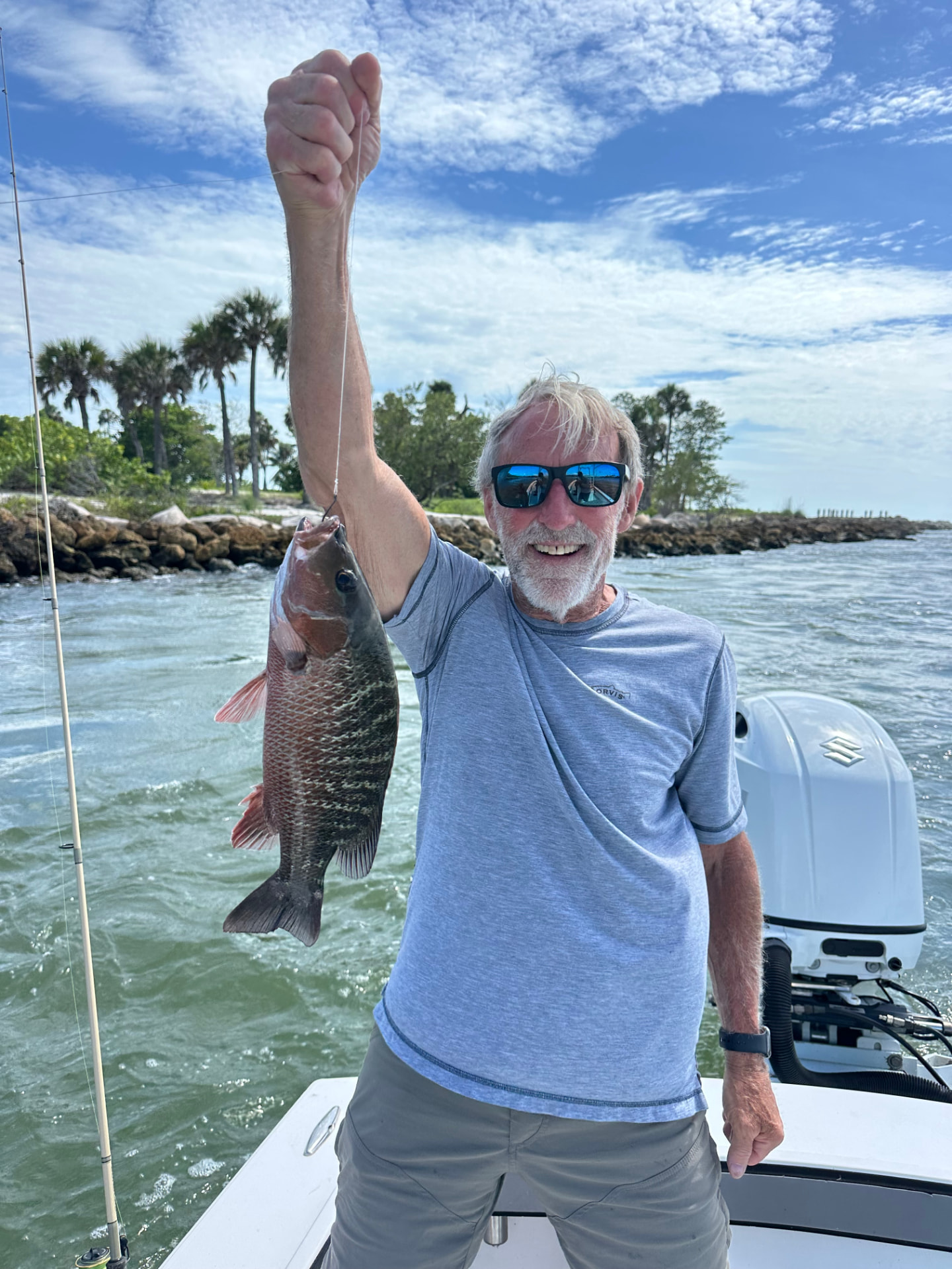 Angler holding up a mangrove snapper caught on a Naples fishing charter