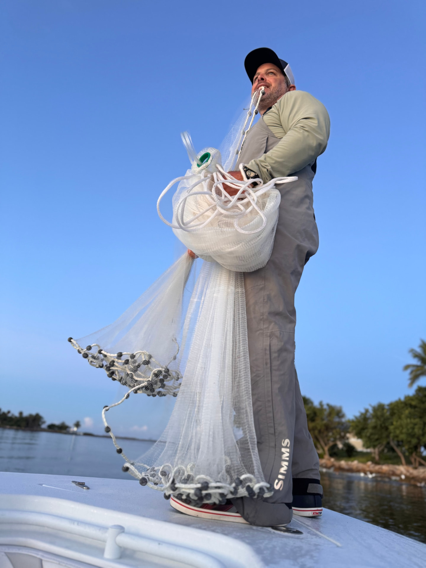 Captain Tony Fontana throwing a cast net aboard his Naples fishing charter